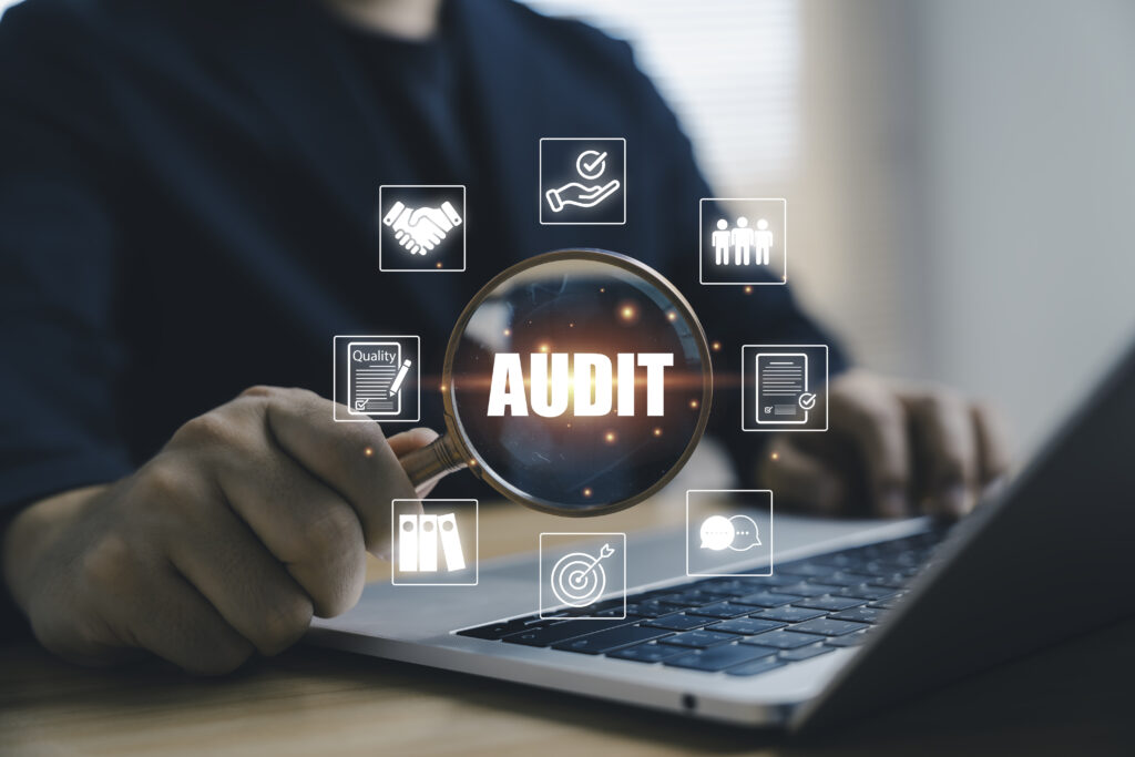 businessman holding magnifying glass with audit wording and icons for quality management compliance evaluation and document review showing the concept of professional inspection and organization